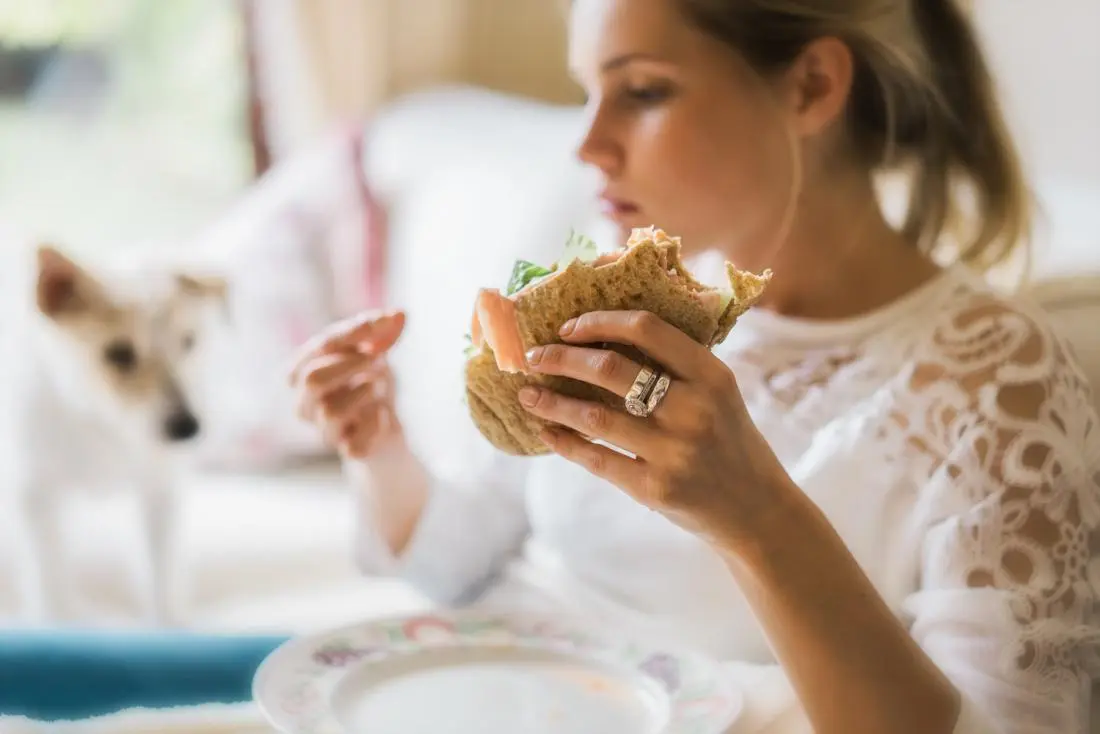woman-experiencing-compulsive-eating-before-period-holding-a-sandwich.webp